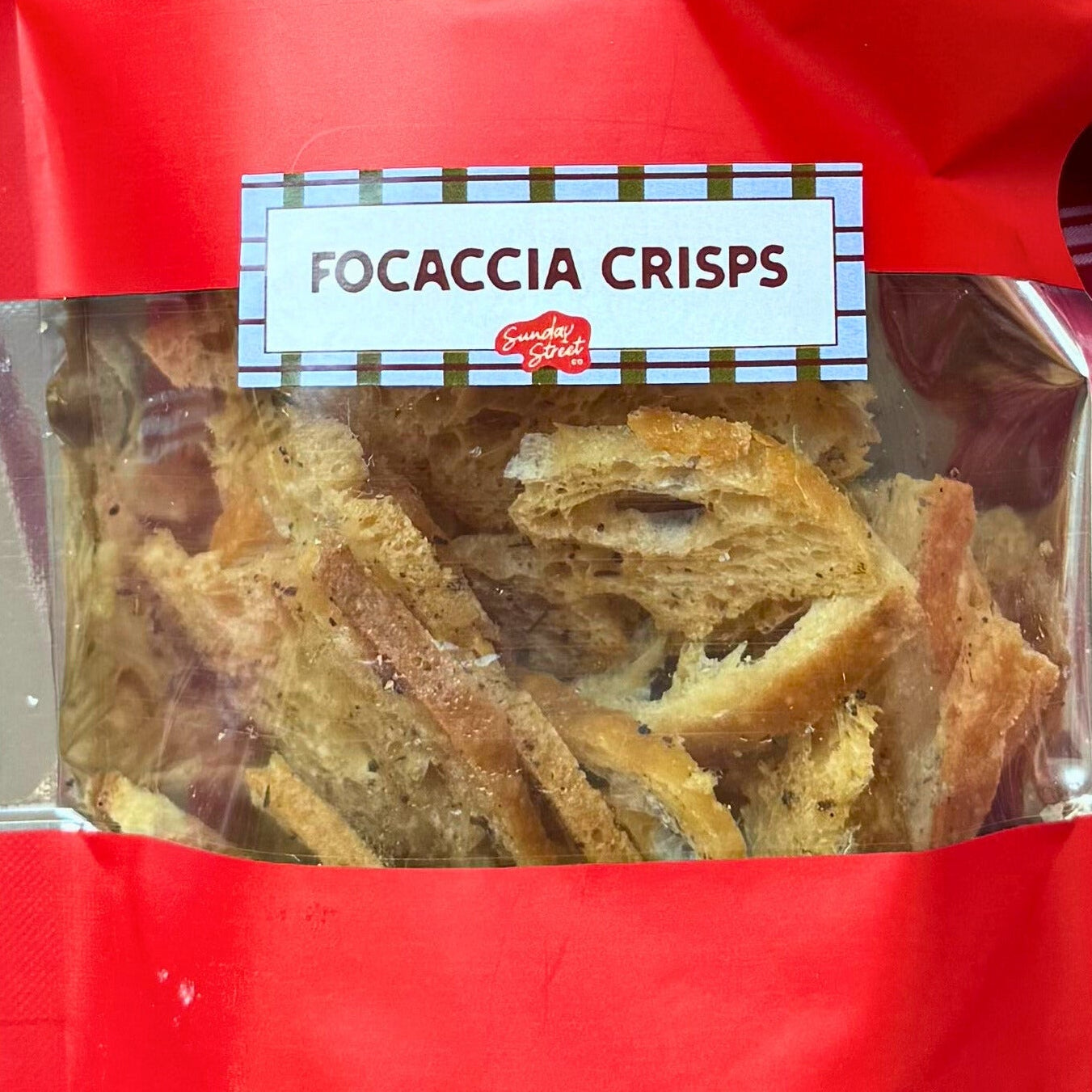 Red bag of focaccia crisps on a red checkered fabric background