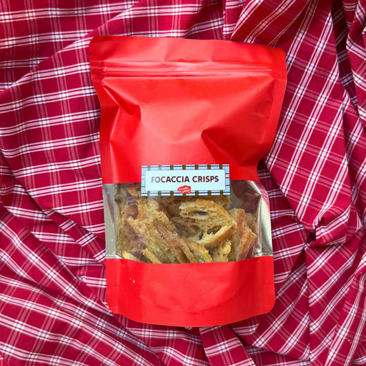 Red bag of focaccia crisps on a red checkered fabric background